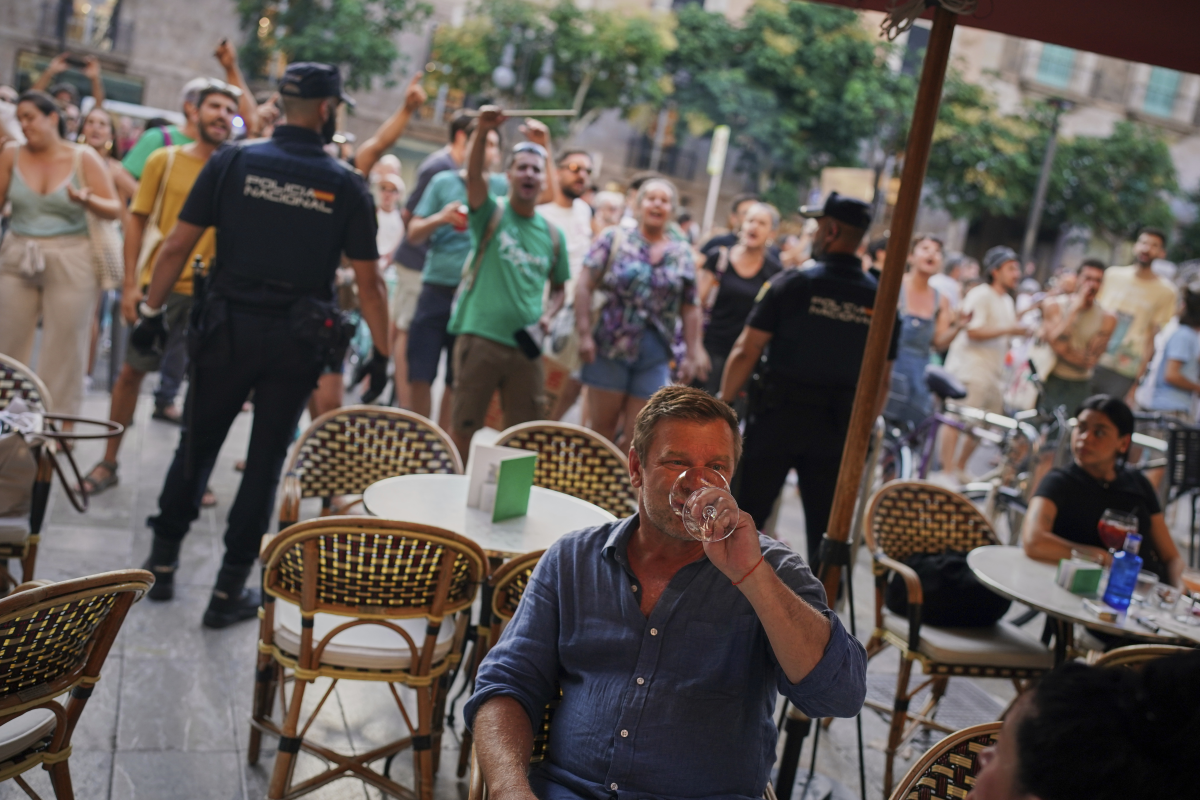 Tourists sit in a restaurant as people protest against overtourism in the Balearic island of Mallorca, Spain on Sunday.
