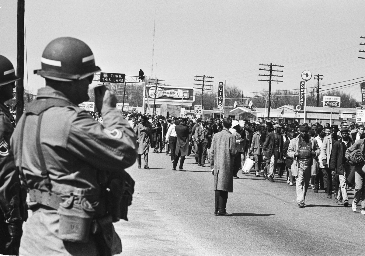 Soldiers watch civil rights protesters walking during the third Selma March in Alabama, on March 25, 1965. President Lyndon Johnson federalized the Alabama National Guard to prevent violence against the marchers.