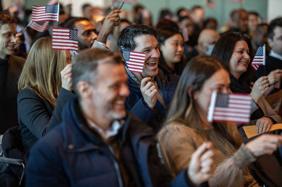 People wave U.S. flags to celebrate becoming U.S. citizens after taking the oath of allegiance during a naturalization ceremony in the jury assembly room at the John Joseph Moakley United States Courthouse in Boston, Mass., in January 2025. In total 102 immigrants from 40 countries became US citizens during the ceremony. (Photo by Joseph Prezioso / AFP) (Photo by JOSEPH PREZIOSO/AFP via Getty Images)