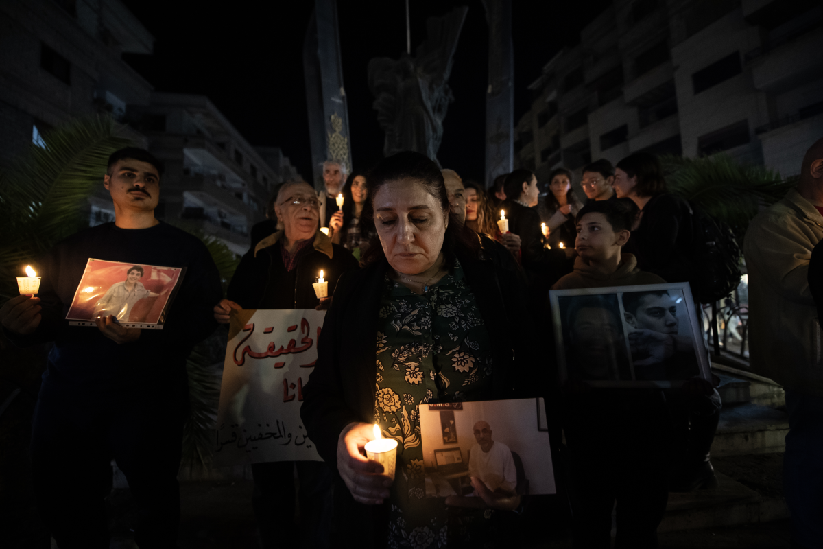 Majida Kaddo holds a photo of one of her missing relatives and a candle at a vigil in Damascus on March 27.