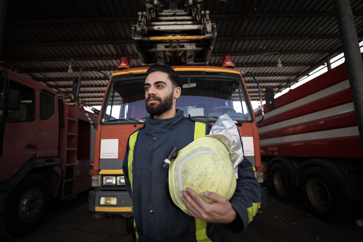 Mohammed Khdeir poses for a portrait in front of a firetruck.