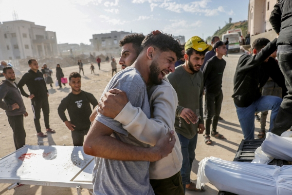 A Palestinian man is comforted as he weeps next to a truck carrying the bodies of the victims of Israeli overnight airstrikes before transporting them for burial on Tuesday. Israeli airstrikes killed more than 400 people and injured hundreds more on one of the most intense strikes in Gaza since the war began in 2023.