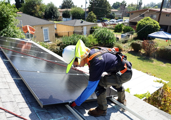 A worker installs no-cost solar panels on the roof of a low-income household in 2023 in Pomona, Calif.