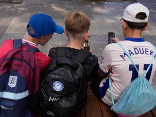 FILE - Three boys use their phones while sitting outside a school in Sydney, Monday, Dec. 8, 2025.
