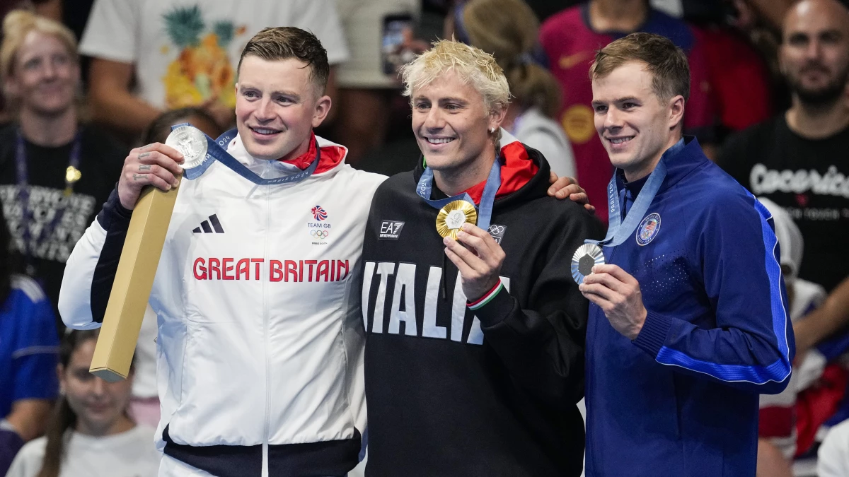 Gold medalist, Nicolo Martinenghi, center, of Italy, stands with silver medalists, Nic Fink, right, of the the United States, and Adam Peaty, of Britain, on the podium after the men's 100-meter breaststroke final on Sunday at the 2024 Summer Olympics.