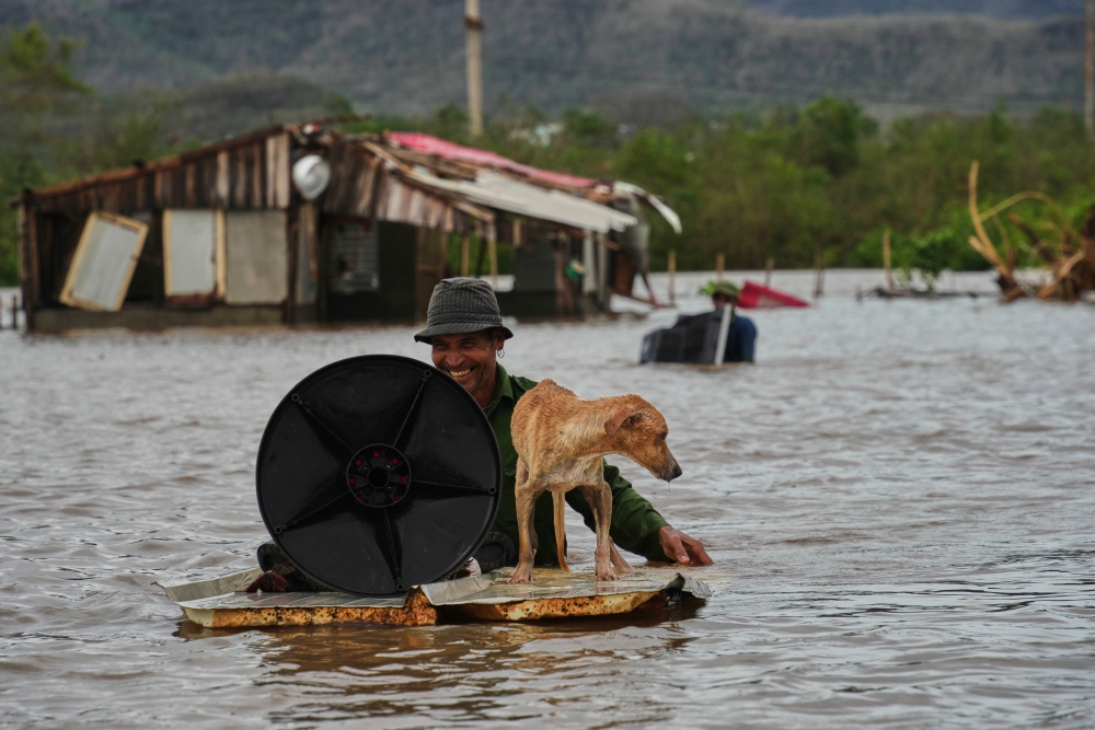 A man wades through floodwaters with his dog and belongings from his home flooded by Hurricane Melissa in Santiago de Cuba on Wednesday. (AP)