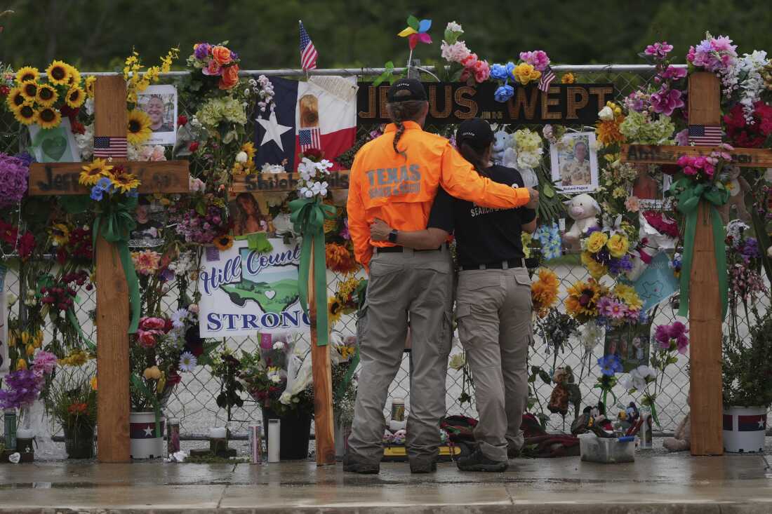 Members of a search and rescue team visit a memorial wall for flood victims in Kerrville, Texas.