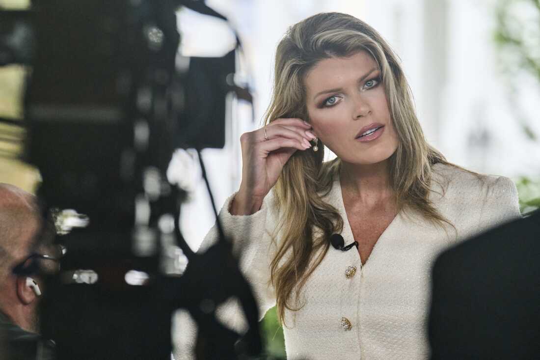 Lindsey Halligan, at the time special assistant to the president, fixes an earring at the end of an interview outside of the White House in August 2025, in Washington.