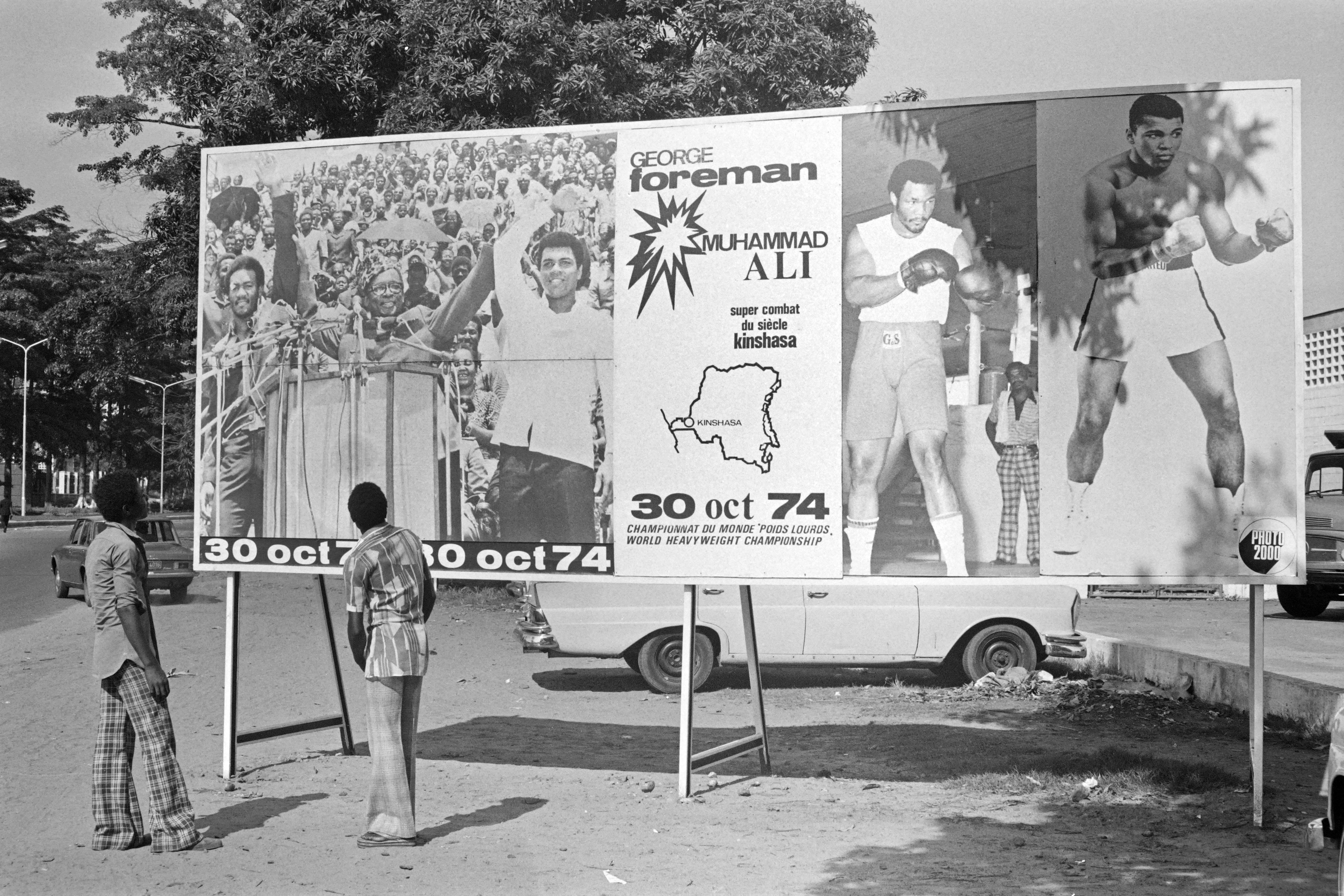 People look at a billboard in Kinshasa on Oct. 30, 1974, announcing the fight between U.S. boxers Muhammad Ali and George Foreman. That day, Ali knocked out Foreman in a clash of titans known as the "Rumble in the Jungle," watched by 60,000 people in the stadium in Kinshasa and millions elsewhere.