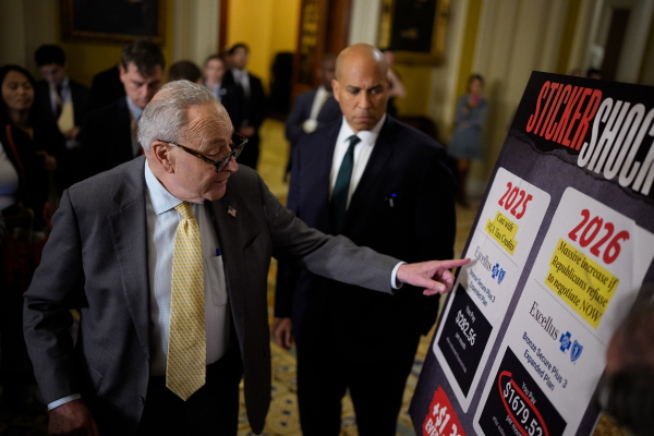 Senate Minority Leader Chuck Schumer, D-N.Y., accompanied by Sen. Cory Booker, D-N.J., points to a poster depicting rising medical costs if Congress allows the Affordable Care Act tax credits to expire as he speaks to reporters at the U.S. Capitol on Oct. 15, 2025.