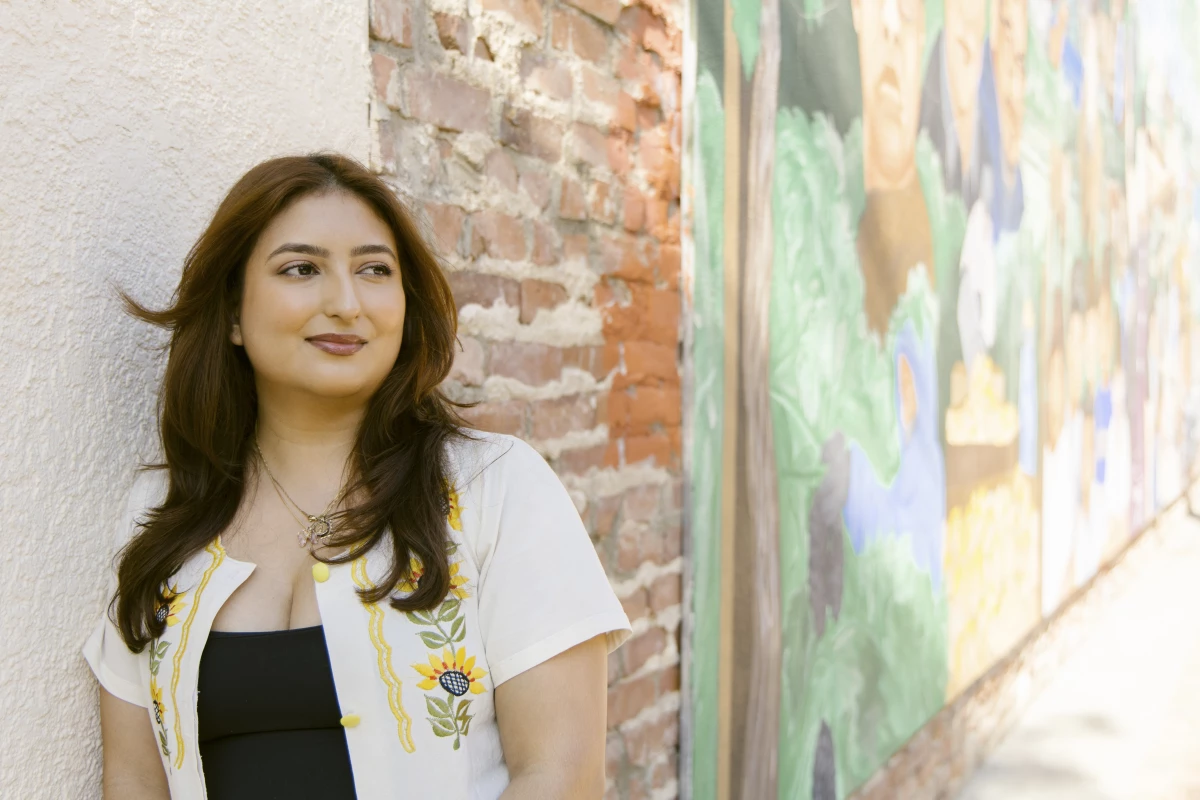 Monike Reynozo, associate director of programs for the non-profit Loud for Tomorrow, stands in front of a mural depicting Cesar Chavez and other leaders of the farm labor movement in downtown Delano, Calif. on March 29.