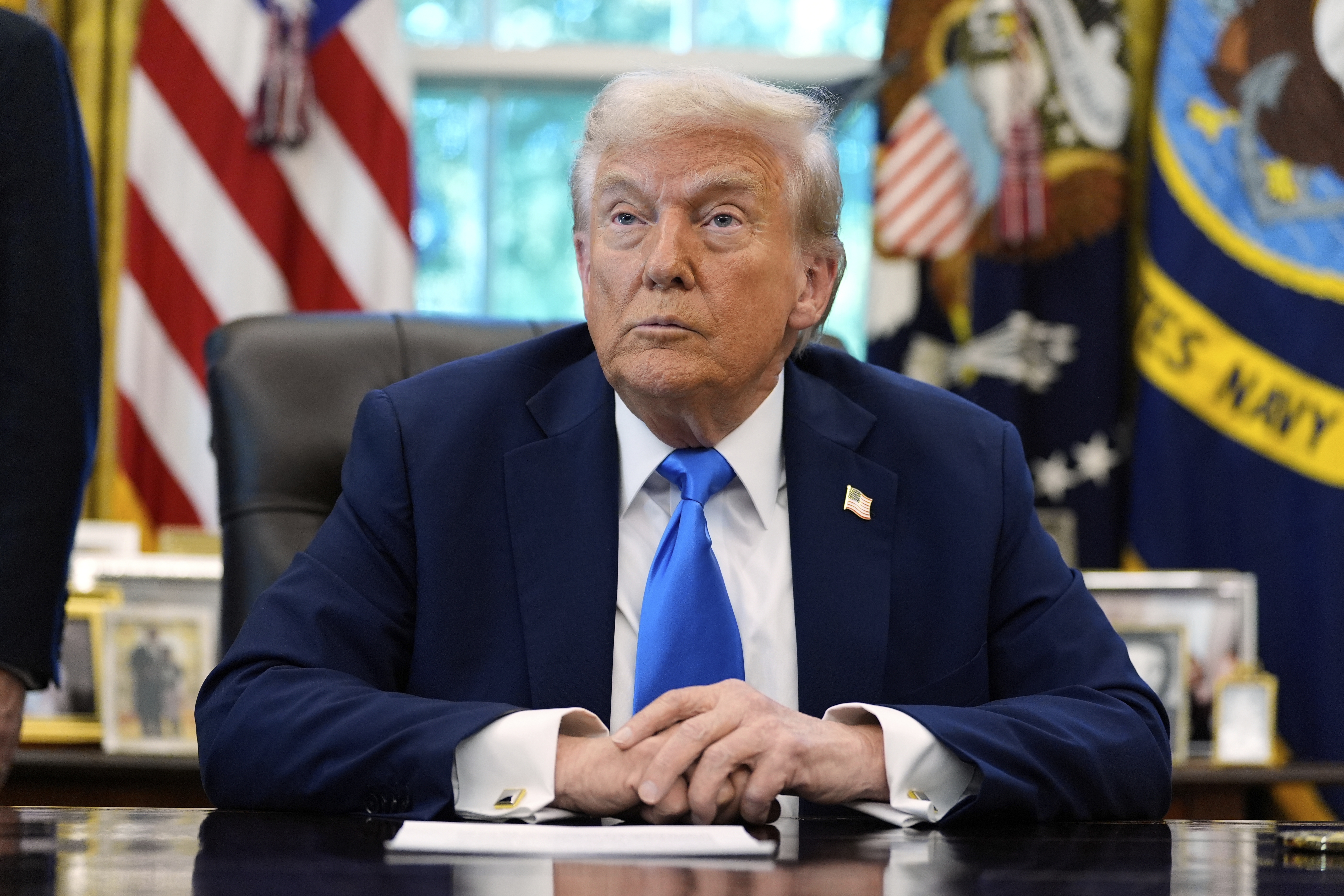 President Donald Trump listens to a reporter's question in the Oval Office of the White House, on Friday. (AP)