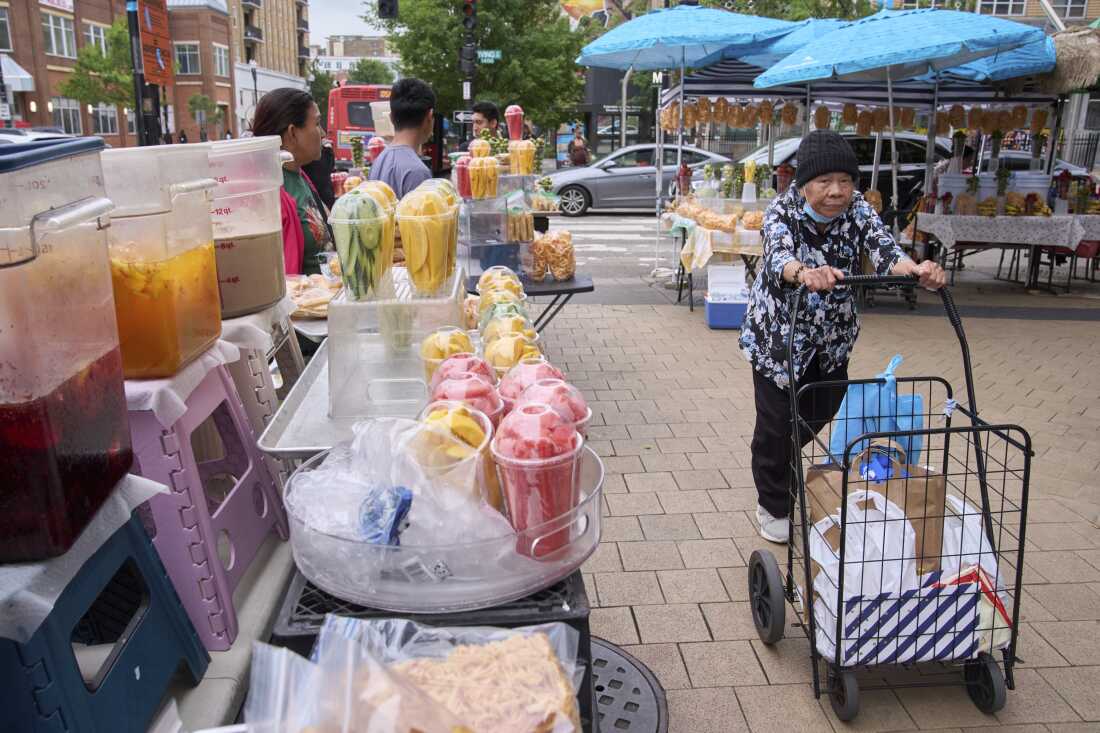 A woman walks past fruit vendors in D.C.'s Columbia Heights, a neighborhood where many Latinos live, on August 19, 2025.