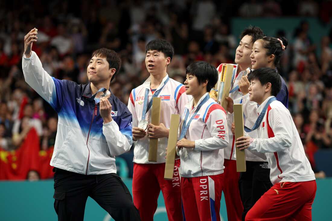 Lim Jong-hoon of South Korea takes a selfie with North Korean silver medalists Kim Kum-yong and Ri Jong-sik, center, with Chinese gold medalists Wang Chuqin and Sun Yingsha flanking South Korean Shin Yu-bin.