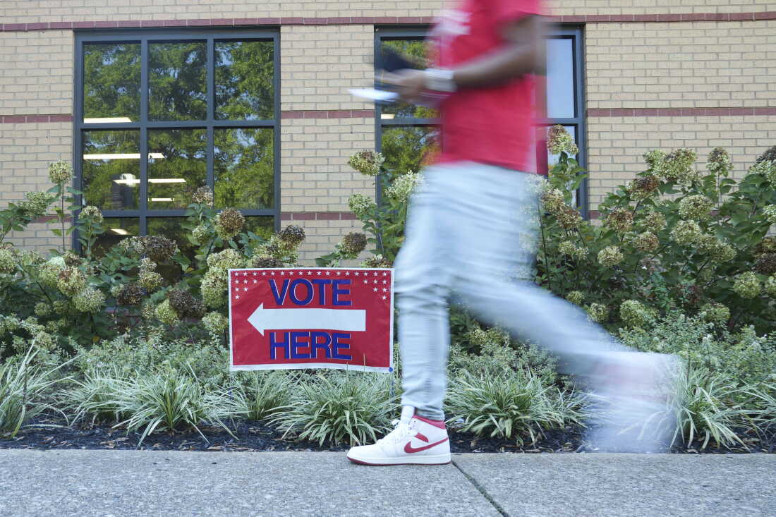 A person walks past a voting sign at the East Point Library on Tuesday, the first day of early voting, in Atlanta.