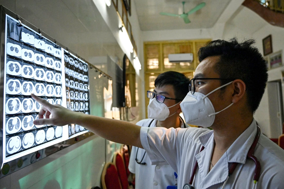 Vietnamese doctor Truong Duc Thai and a colleague check the X-ray film of a drug-resistant tuberculosis patient at National Lung Hospital in Hanoi. TB kills more people than any other infectious disease. A new study projects that U.S. aid cuts will worsen its toll.