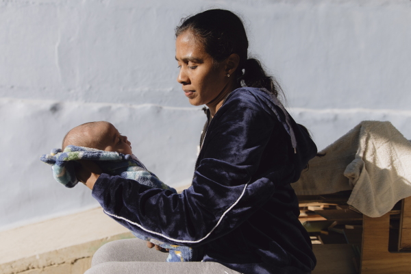 Cindy Alamei Patiño holds her recently born baby at the Embajadores de Jesús church in Tijuana, Mexico, on Dec. 6, 2024. The mother of two traveled with her husband, Andres Patiño, from Colombia and is hoping to be in the U.S. before the new administration takes office in the U.S. Zaydee Sanchez for NPR