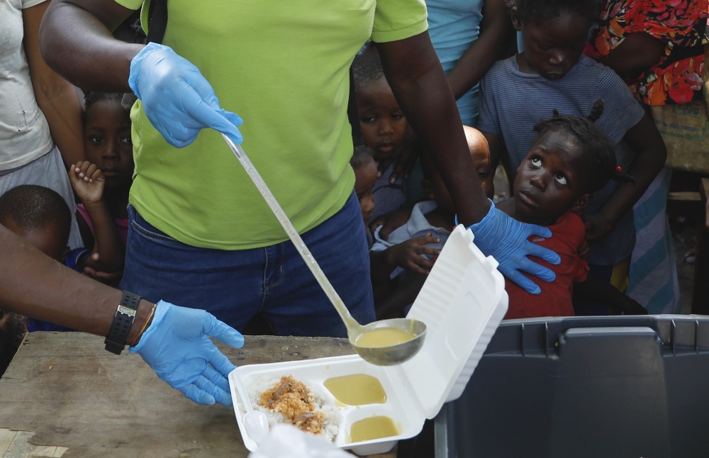 A server ladles soup into a container as children line up to receive food at a shelter for families displaced by gang violence, in Port-au-Prince, Haiti, in March 2024. Gang violence in Haiti has displaced over 300,000 children since March, according to a new report from the U.N. children's agency released late Tuesday. (AP)