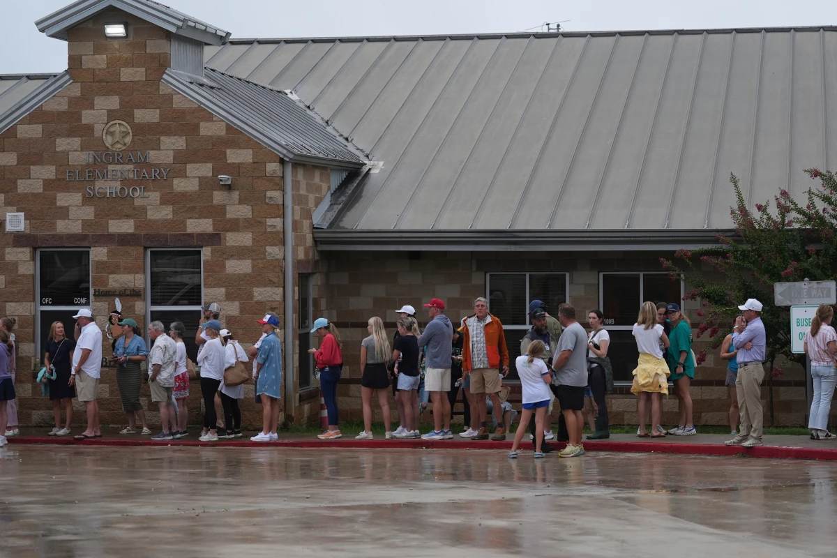 Families line up at a reunification center after flash flooding hit the area in Ingram, Texas.