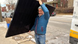 Solar States owner Micah Gold-Markel carries a solar panel from a truck to the house where it will be installed.