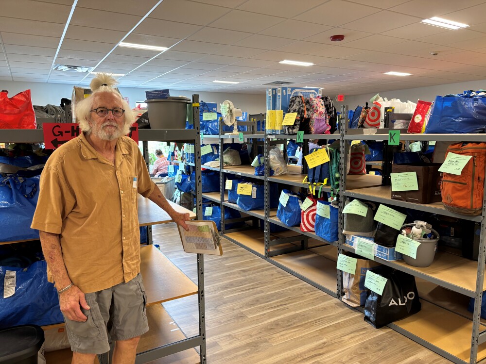 Lee Cooper, a volunteer at Maine Needs, stands near bags of filled orders. (Maine Public Radio)