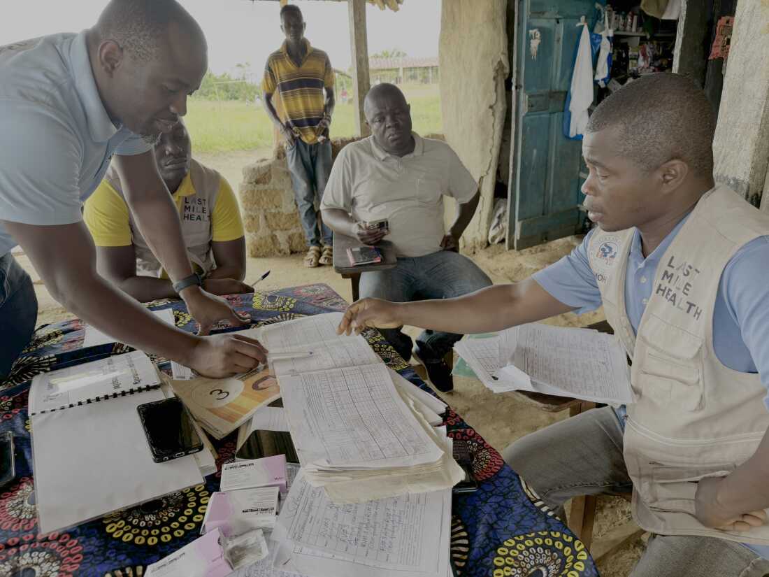Genesis Whegelee (right, in vest) has been a community health worker for Last Mile Health in Rivercess County, Liberia, since 2018. He visits households to keep an eye on sick children, pregnant moms and anyone with a problem that needs diagnosing.