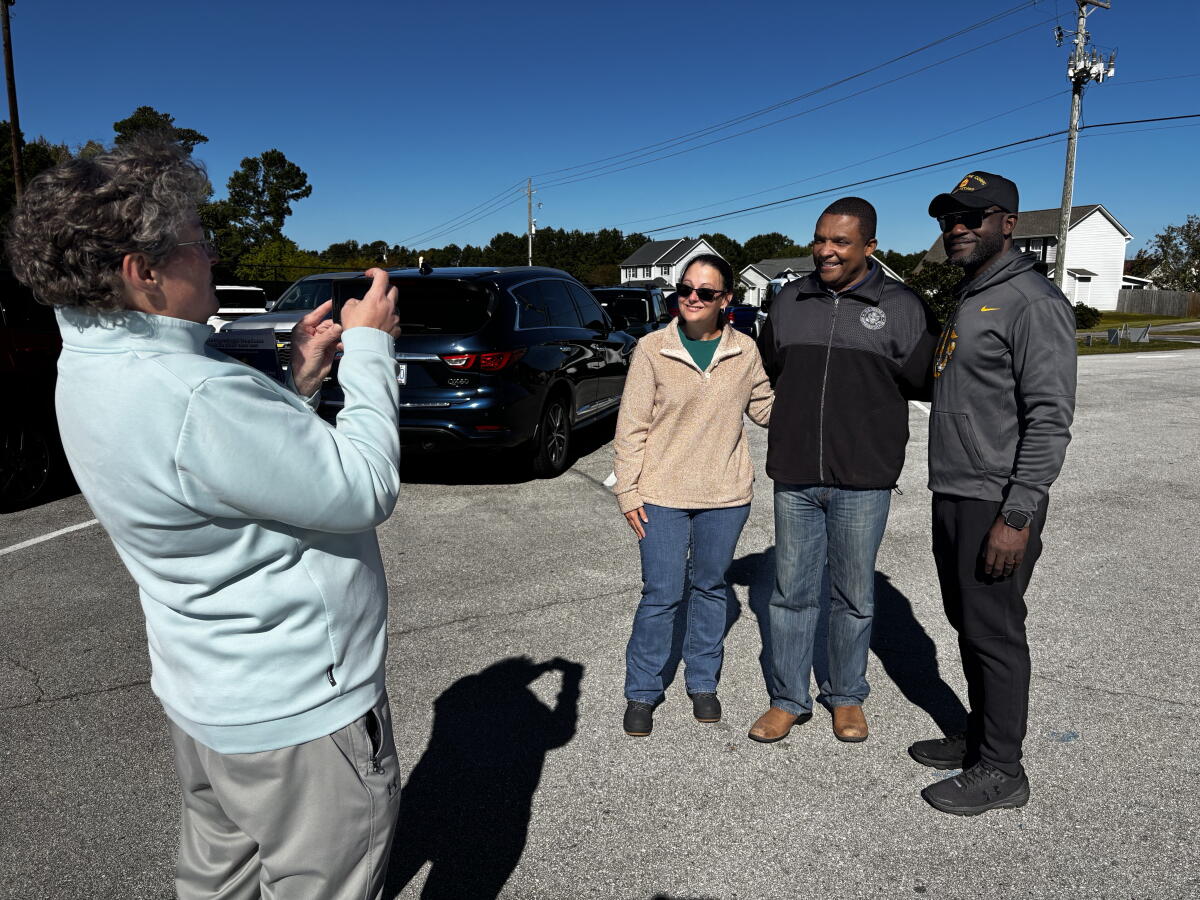 A volunteer snaps a photo of Democratic Rep. Don Davis with Onslow County Board of Commissioner candidates Rebecca Cooper and Michel Leandre Jr. outside an early voting location in Swansboro, N.C. Onslow is one of six counties added to North Carolina's 1st District in the latest redraw of congressional district lines.