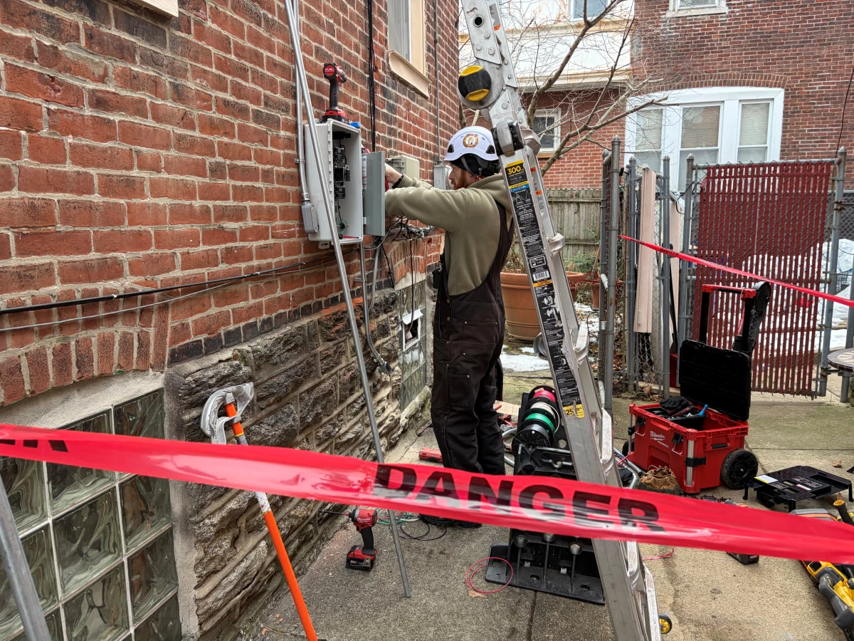 Solar States employee Doug McIntyre installs wiring for a new rooftop solar project in North Philadelphia.