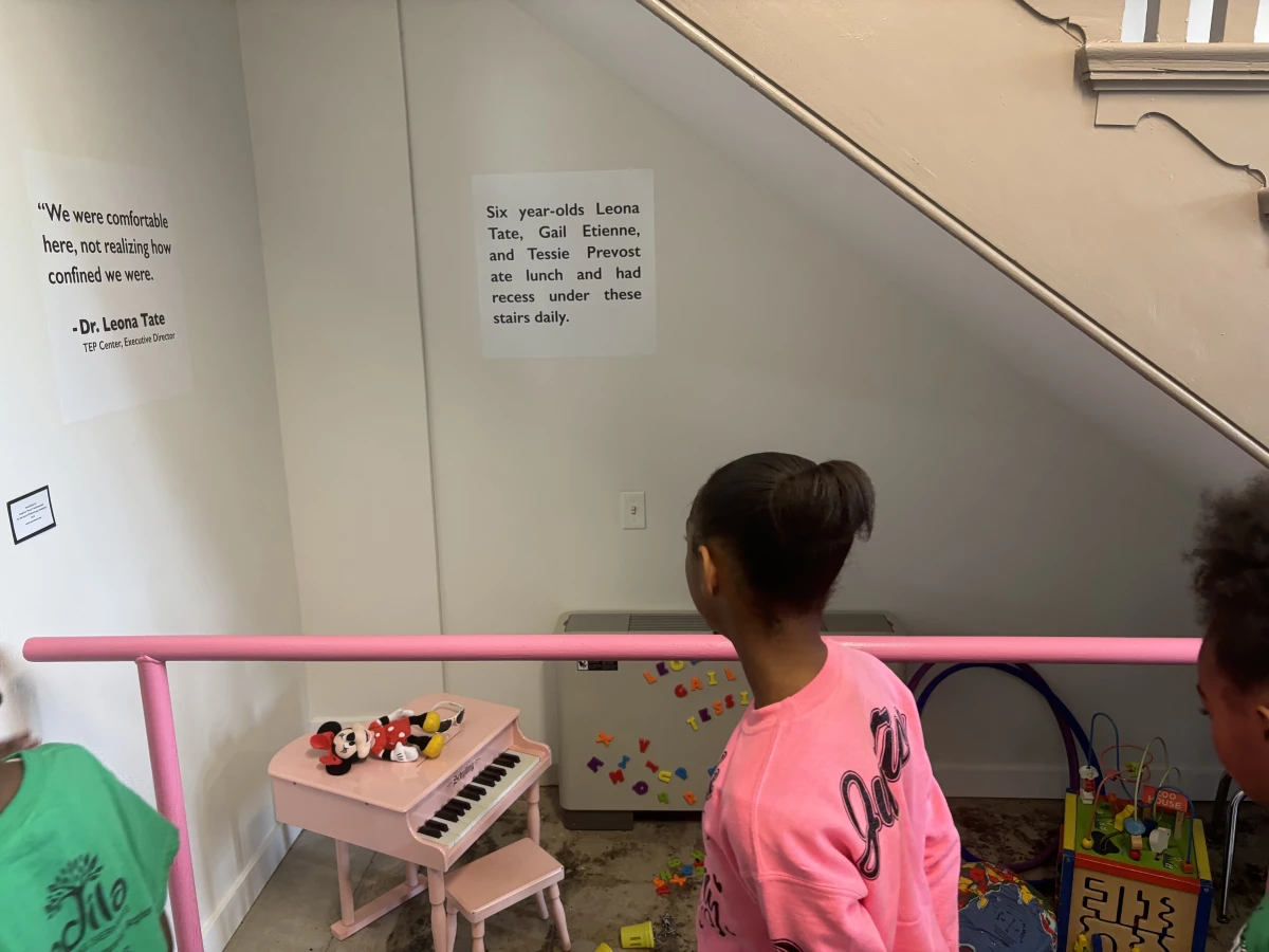 Students look at the area under the stairs where the 'McDonogh 3' where confined to eat and play.