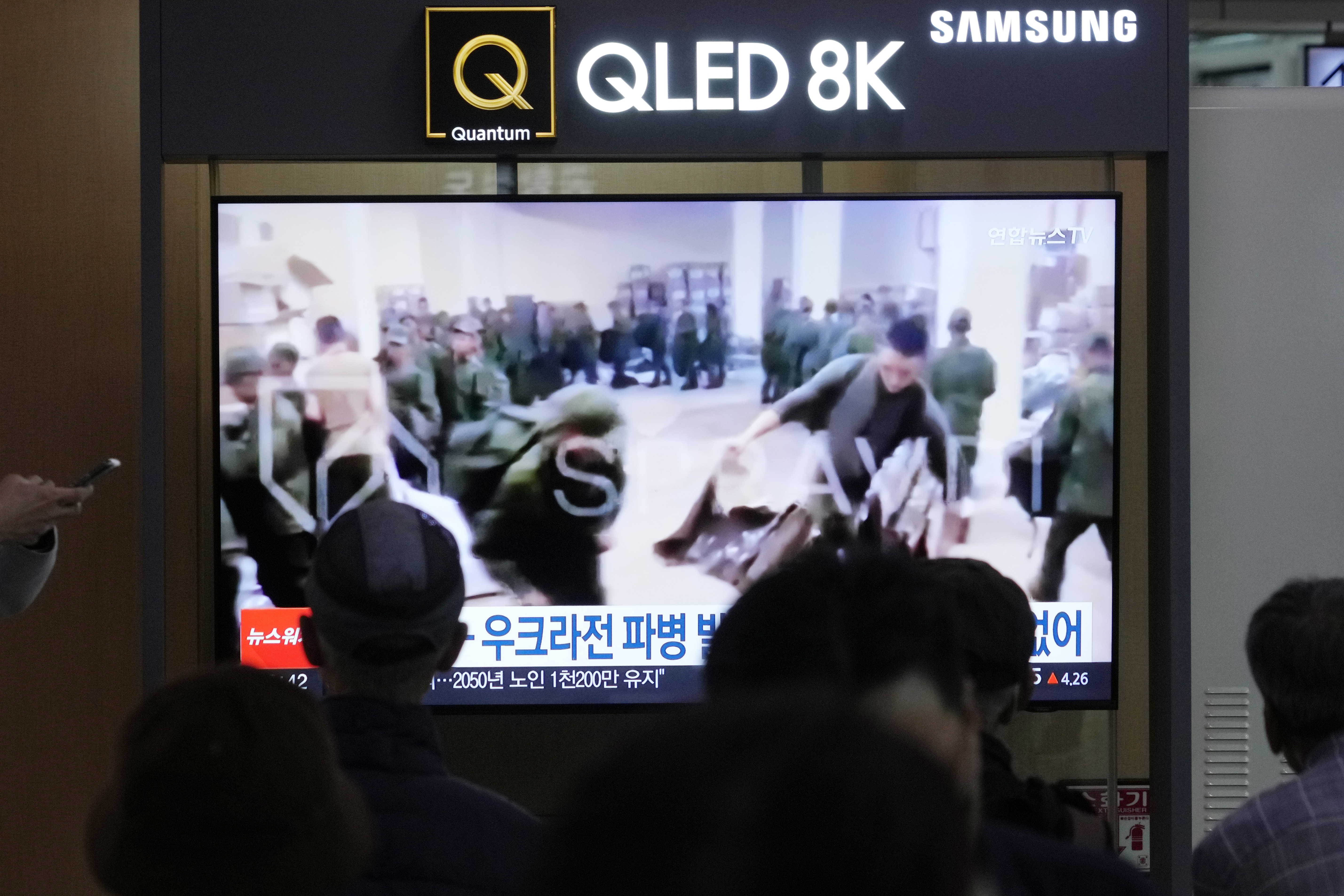 A TV screen shows an image of soldiers believed to be from North Korea stand in line to receive supplies from Russia during a news program at Seoul Railway Station in Seoul, South Korea, on Monday. (AP)