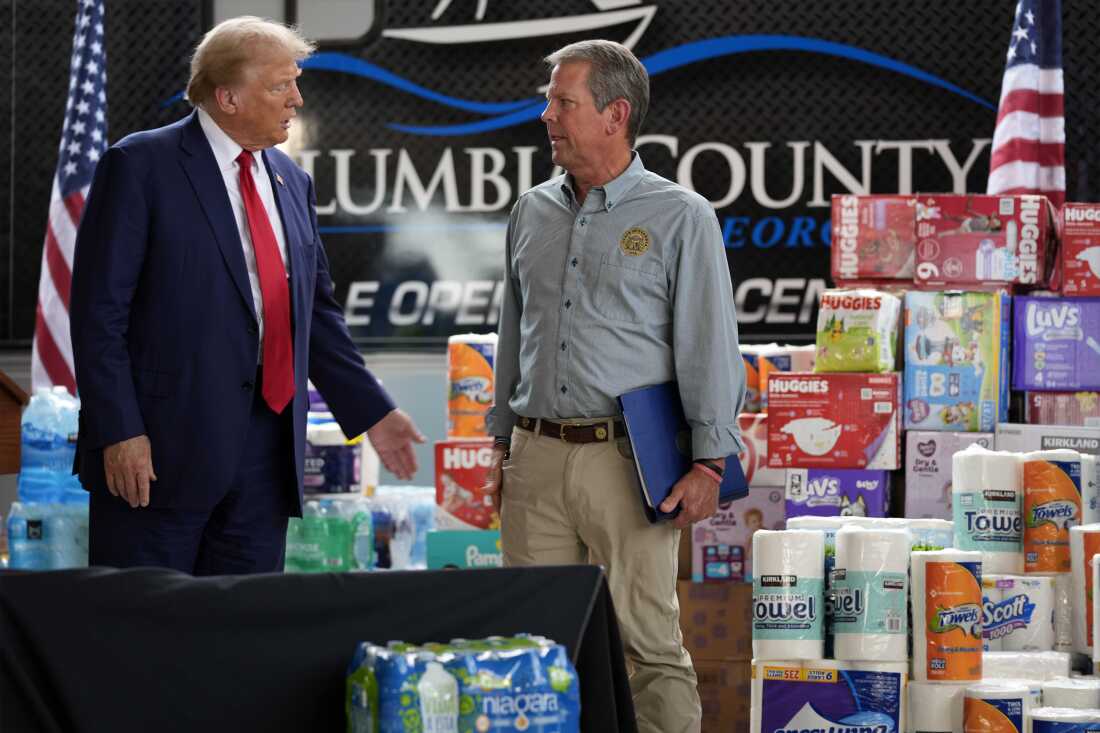 Former President Donald Trump talks with Georgia Gov. Brian Kemp after speaking at a temporary relief shelter in Evans, Ga., an area impacted by Hurricane Helene.