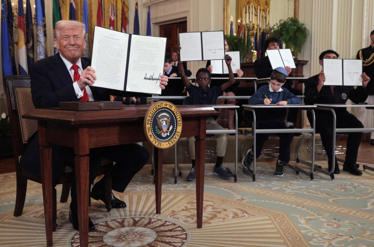 President Donald Trump signs an executive order to reduce the size and scope of the Education Department alongside school children signing their own versions, during a ceremony in the East Room of the White House on March 20.