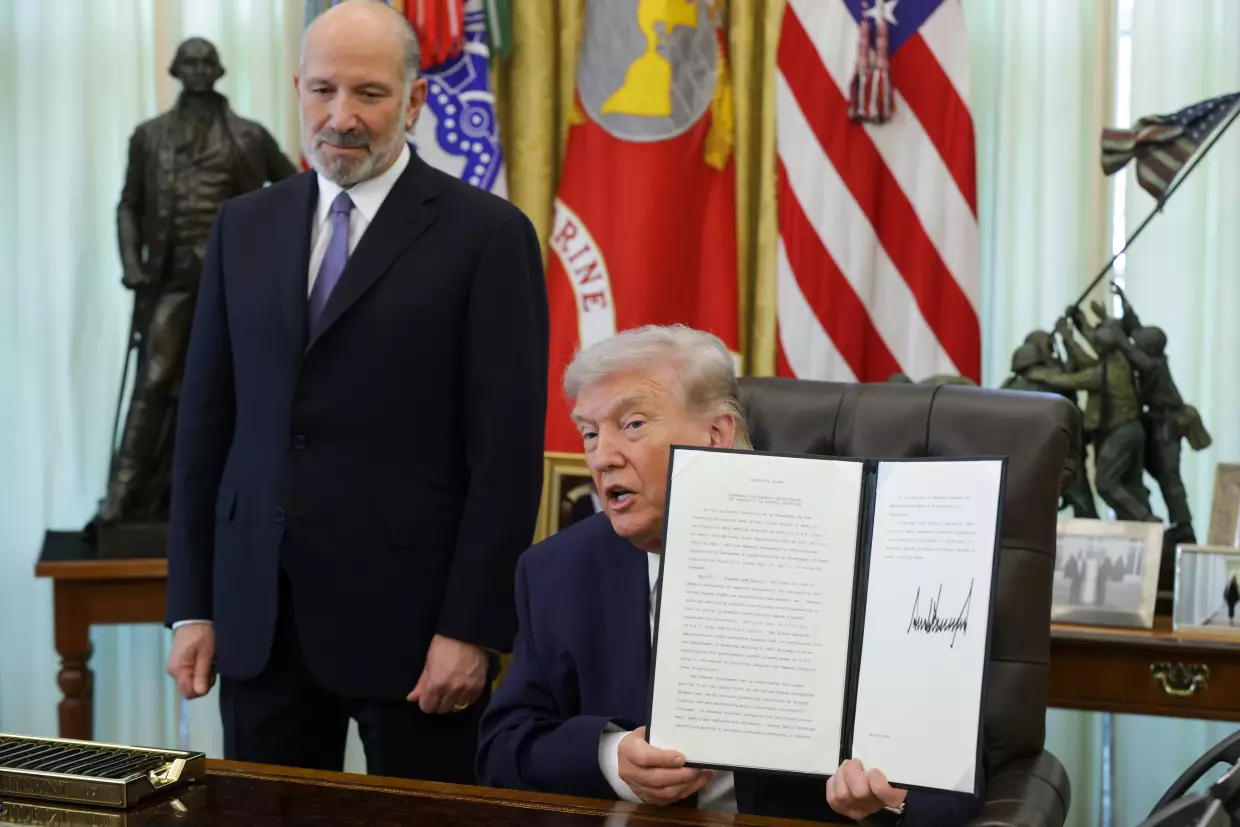President Trump holds up an executive order to limit mail-in voting as Commerce Secretary Howard Lutnick looks on in the White House's Oval Office in March.