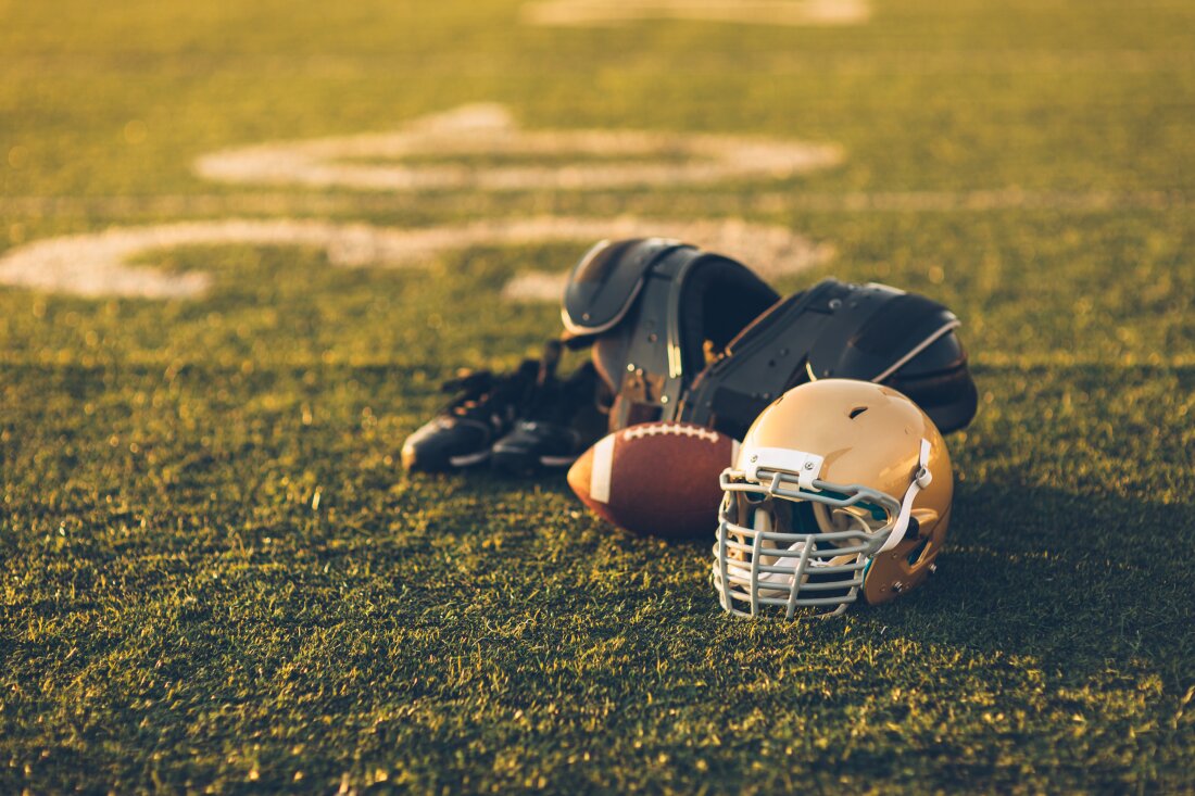 A football, helmet and other football gear are shown on a field.