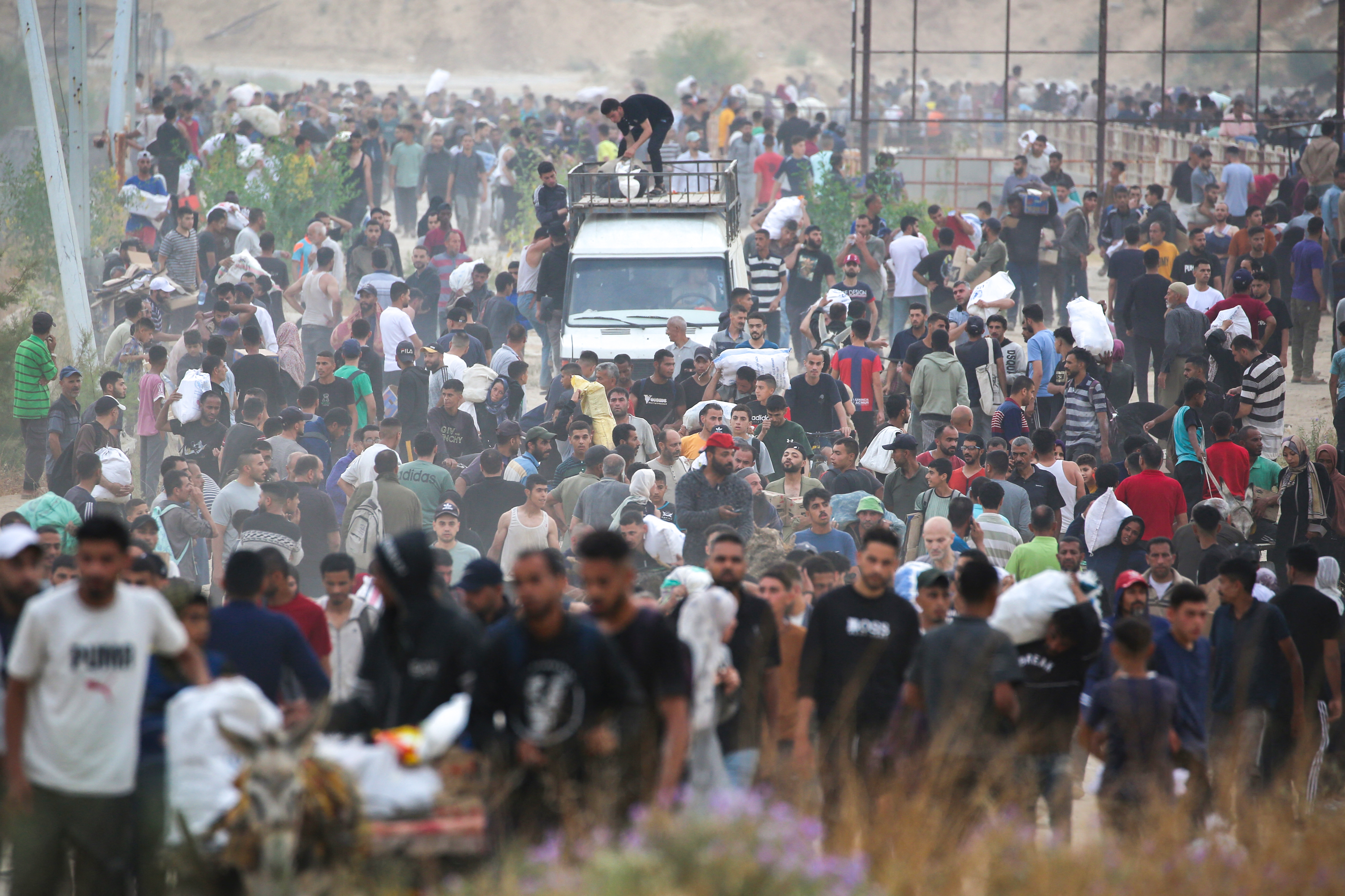 People carry relief supplies from the Gaza Humanitarian Foundation (GHF), a private U.S.-backed aid group that has bypassed the long-standing United Nations-led system in the territory, as displaced Palestinians return from an aid distribution center in the central Gaza Strip, on June 8.