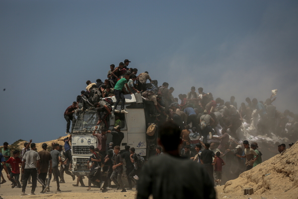 In this photo, Palestinian men and boys swarm on, around and on top of an aid distribution truck in Gaza City on July 27, 2025.
