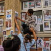 A young boy is helped by a women to put up a photograph of her missing relative on a wall alongside photographs of missing and deceased people displayed outside a government hospital in Kathmandu, Nepal, Sunday, Aug. 30, 2026.