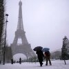 People walk near the Eiffel Tower during a snowfall Wednesday, Jan. 7, 2026 in Paris. 