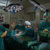 Medical workers surround a patient lying on a table in an operating room.