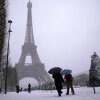 People walk near the Eiffel Tower during a snowfall Wednesday, Jan. 7, 2026 in Paris. 