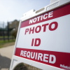 A voter walks past a sign that says "Notice: Photo ID required."