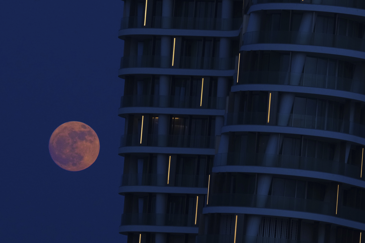 The strawberry moon rises behind a tower at a marina in the southeast resort town of Ayia Napa in the eastern Mediterranean island of Cyprus.