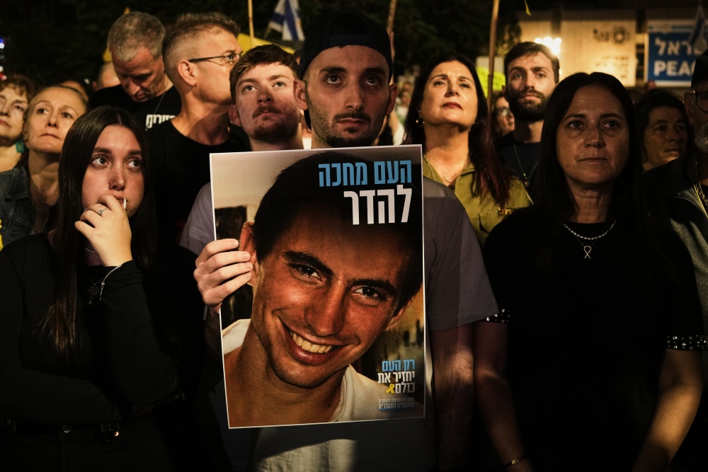 Freed Israeli hostage Matan Angrest holds a photo of Hadar Goldin, an Israeli soldier killed in 2014 whose body has been held in Gaza since then, during a rally calling for the return of the deceased hostages who are held by Hamas in the Gaza Strip, in Tel Aviv, Israel, Saturday, Nov. 8, 2025. (AP)