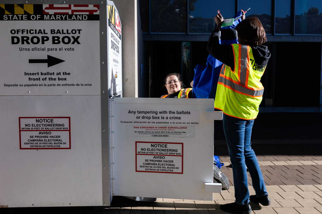 Election workers remove ballots from a drop box outside the polling center at the Silver Spring Civic Building on Oct. 22 in Silver Spring, Md.