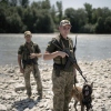 Ukrainian border guards pose with their dog on a pebble beach on the Tisza River bordering Romania, in Velykyi Bychkiv, Ukraine, on July 10.