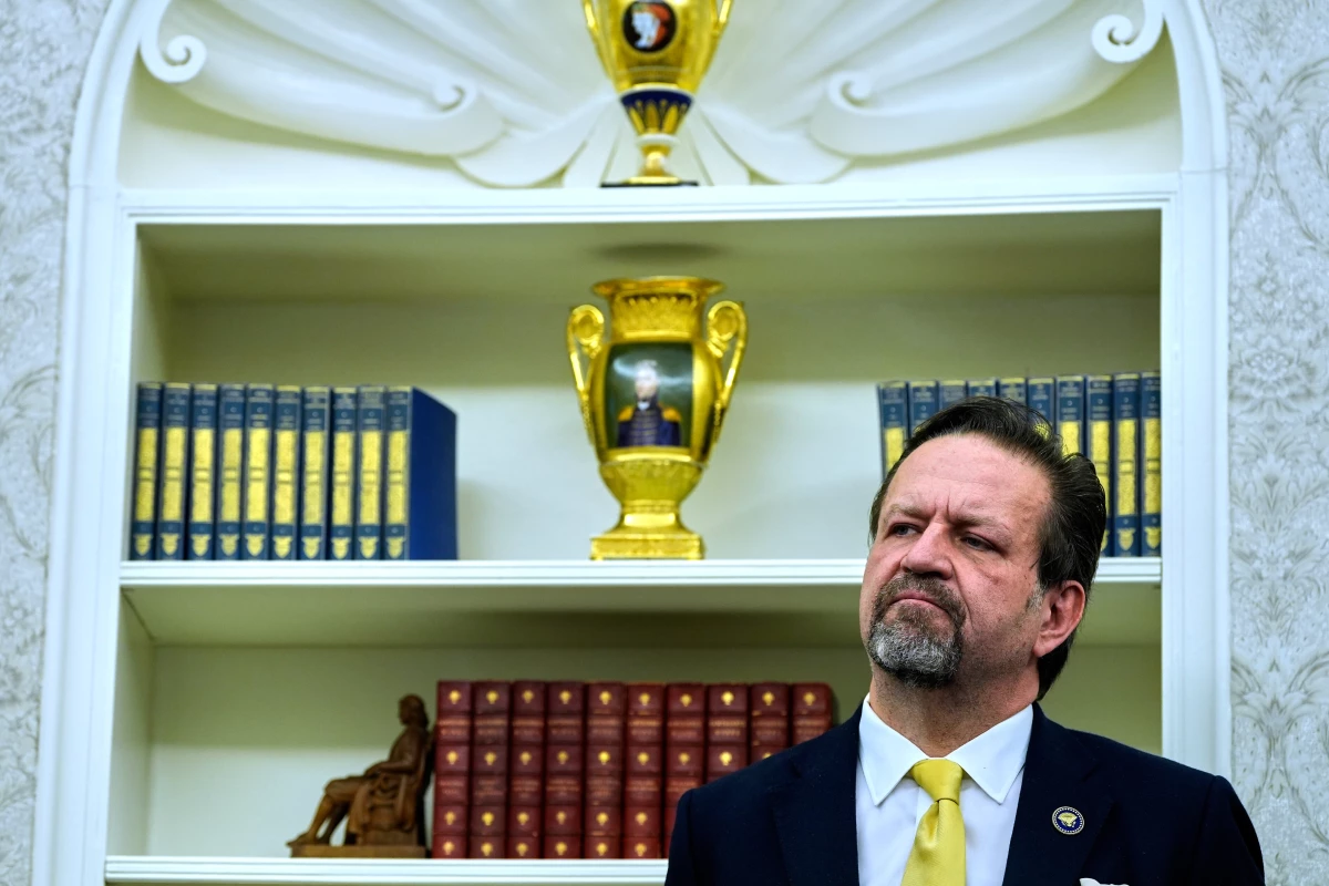 Sebastian Gorka listens as President Donald Trump speaks with reporters after signing executive orders in the Oval Office of the White House, April 23, 2025, in Washington.