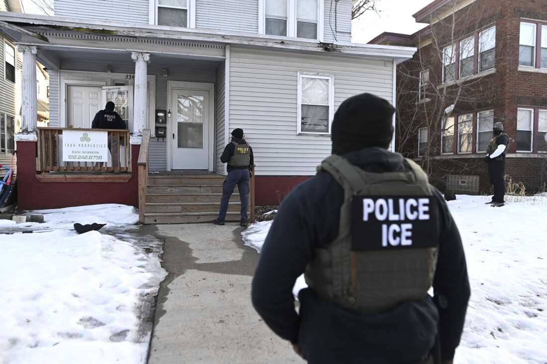 ICE agents approach a house before detaining two people on Jan. 13 in Minneapolis.