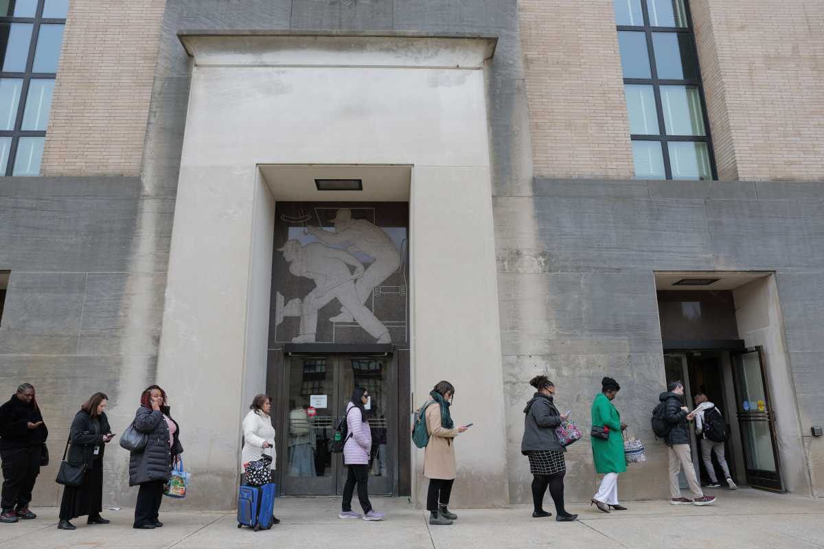 Employees of the Department of Health and Human Services stand in line to enter the Mary E. Switzer Memorial Building on April 2. Layoffs began earlier this week at the agency after it was announced last week that the Trump administration plans to cut 10,000 HHS jobs