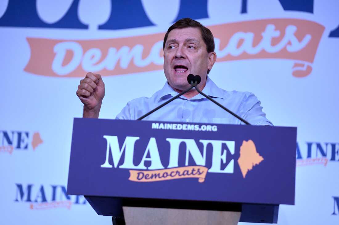 Former Maine Senate President Troy Jackson holds a microphone as he speaks at a rally organized by local unions on May 1 in Portland, Maine. A poster on the lectern says "solidarity."