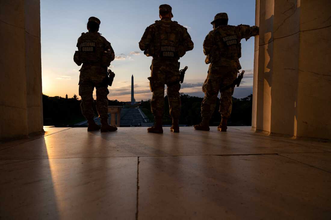 The Washington Monument is seen in the distance as members of the National Guard stand atop the steps at the Lincoln Memorial at sunrise on the National Mall in Washington, DC, on July 23, 2026.